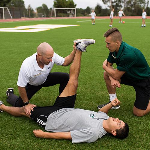 Athletic trainers helping soccer play stretch